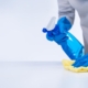 Side view of someone cleaning a surface using disinfectant spray and a cloth